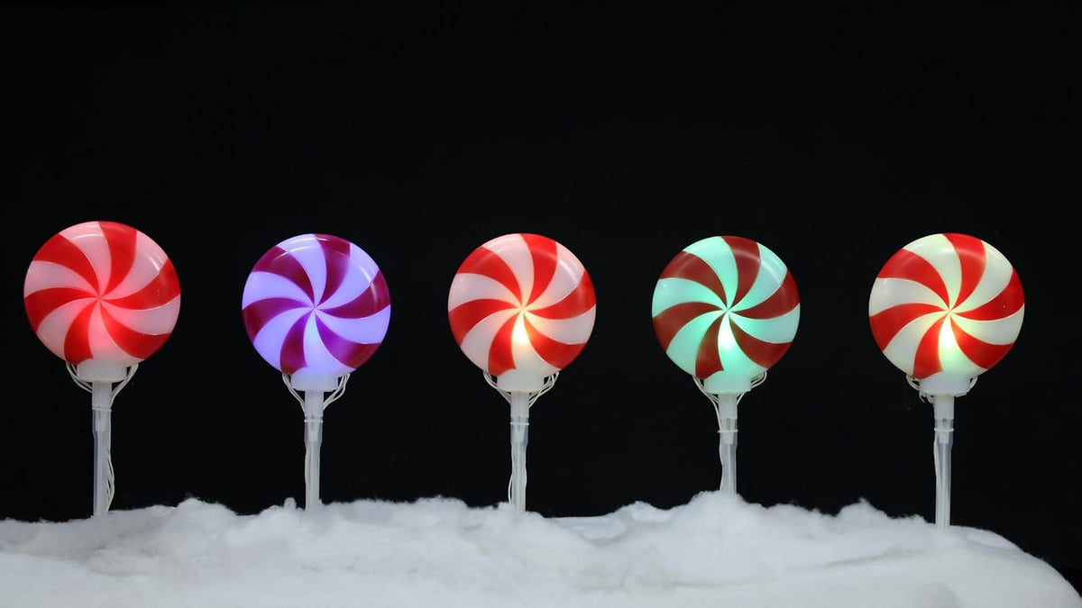 Swirl lollipop pathway lights glowing along a snowy walk