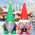 Two inflatable Christmas gnomes in tall green and red hats in the snow