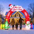 Tall red inflatable Merry Christmas archway with a family walking through