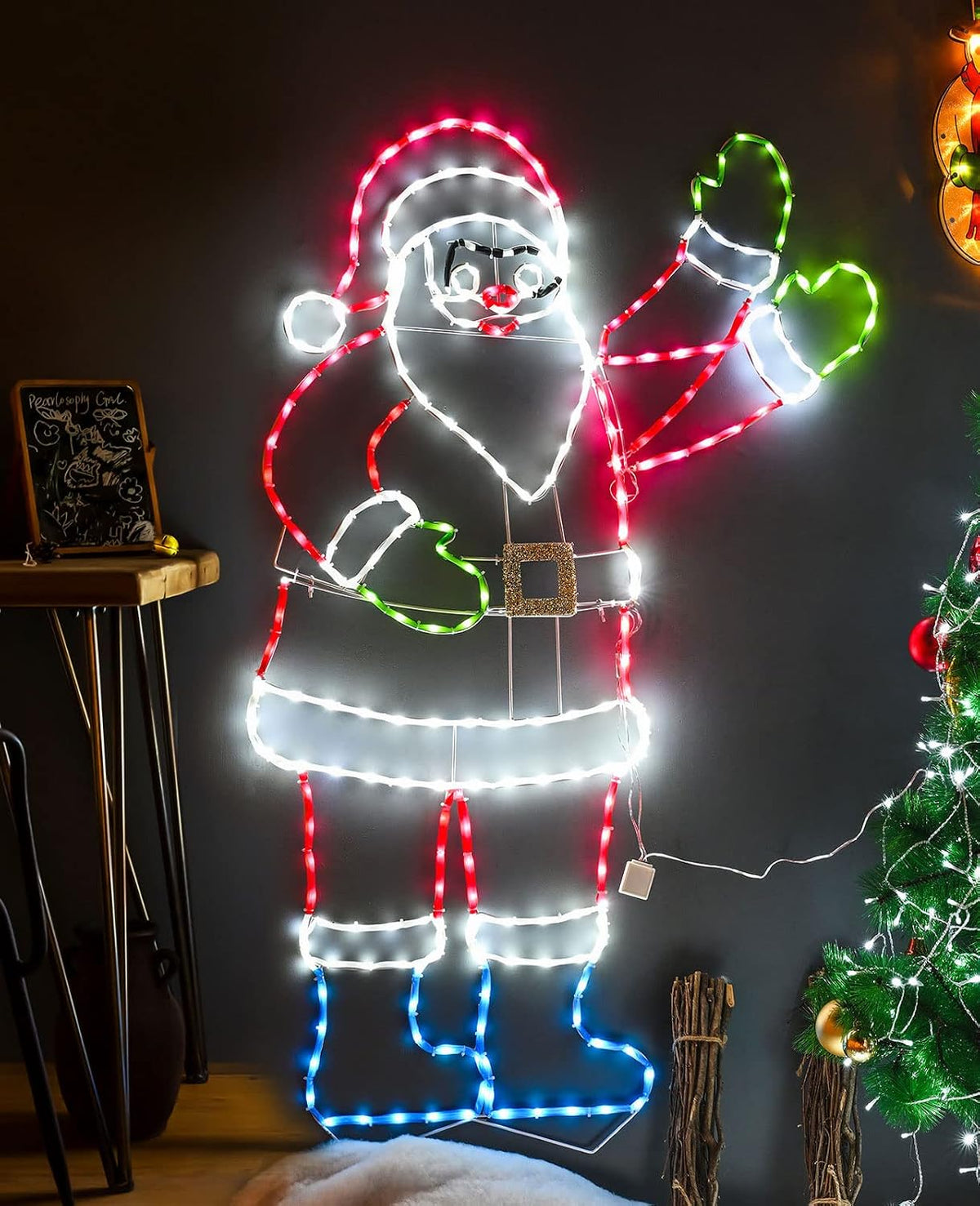 Neon-style LED outline of Santa waving beside a lit tree