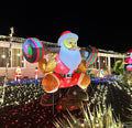 Inflatable Santa squatting with a barbell in front of a lit house