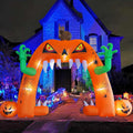 Orange inflatable jack-o'-lantern archway with monster hands over a lit house