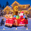 Inflatable Santa in a sled with two reindeer and gifts in a snowy yard